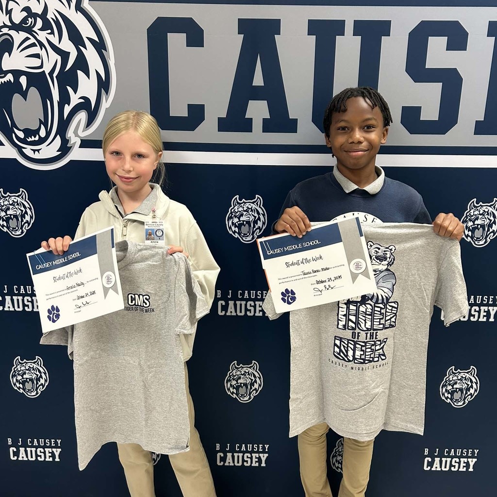 2 students holding up t-shirts and certificates
