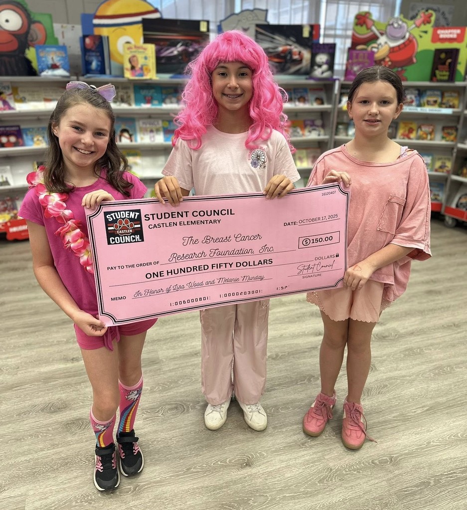 Three girls wearing pink (and one in a pink wig) holding a large check