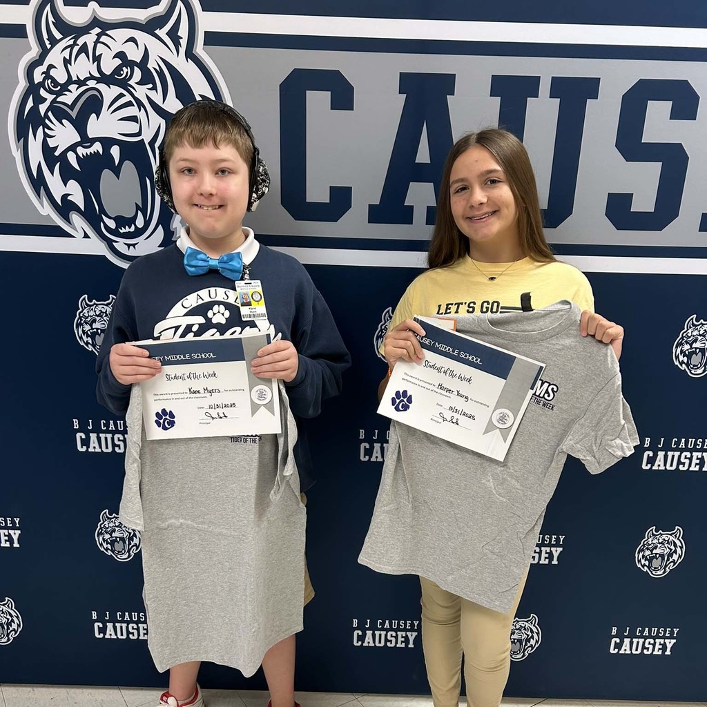 2 students holding up t-shirts and certificates