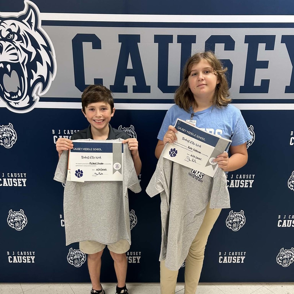 2 students holding up t-shirts and certificates