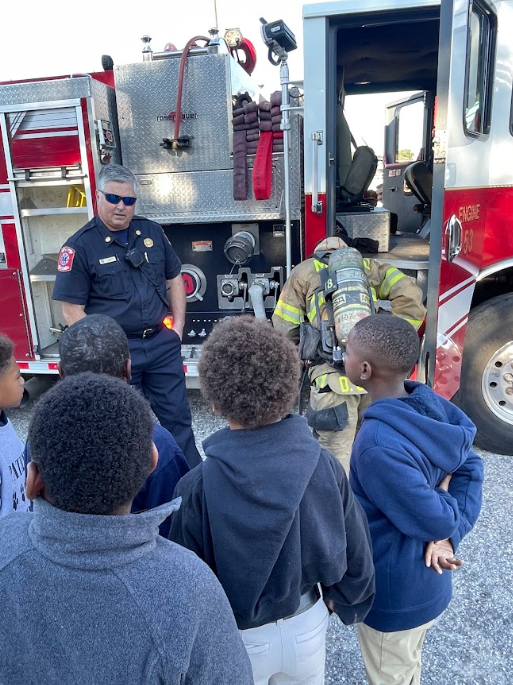 Students standing outside listening to the fireman speak about the firetruck