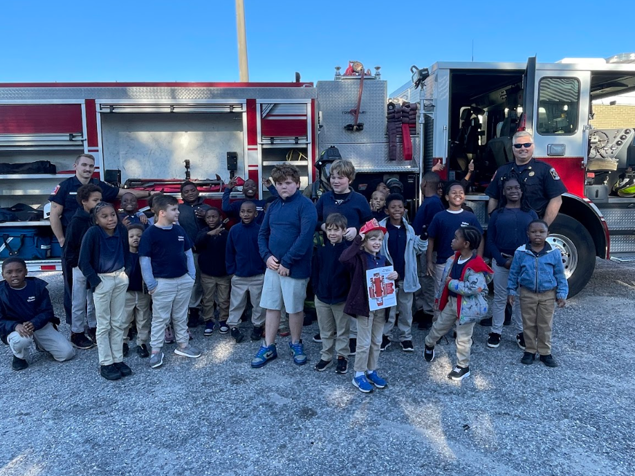 Student standing in front of the fire truck with the firefighters