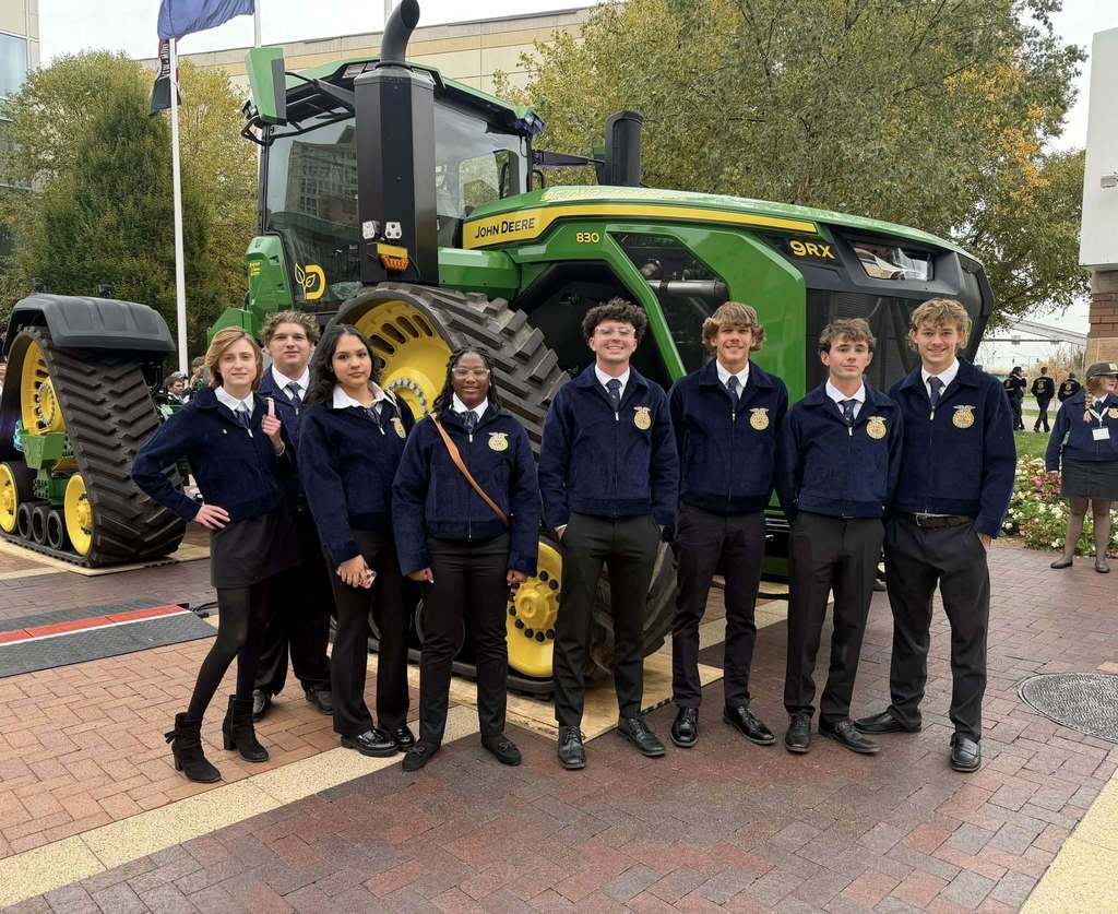 A group of students standing in front of a John Deere tractor
