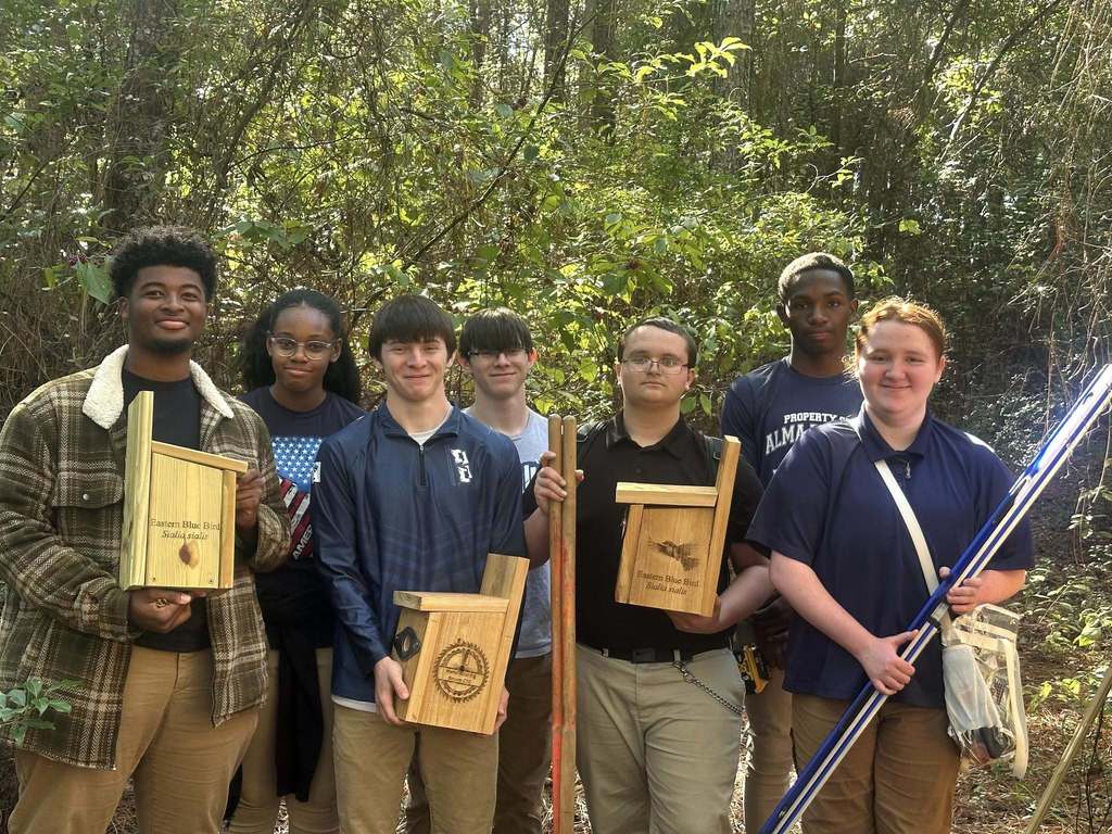 A group of students holidng birdhouses they built