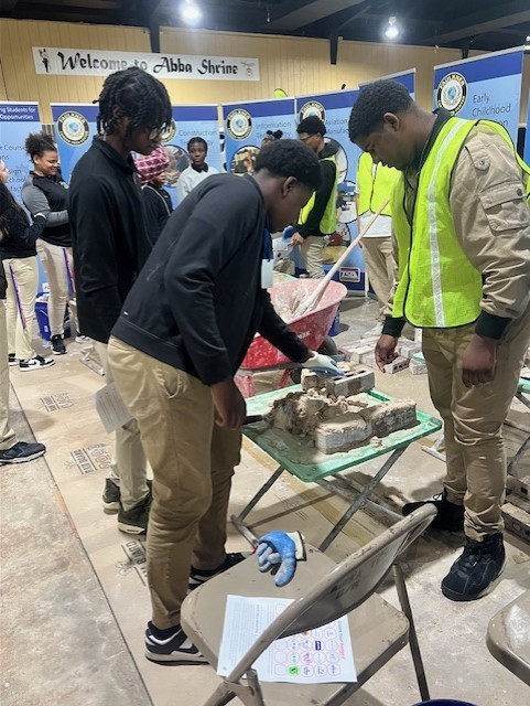 masonry student assisting middle school student with demo