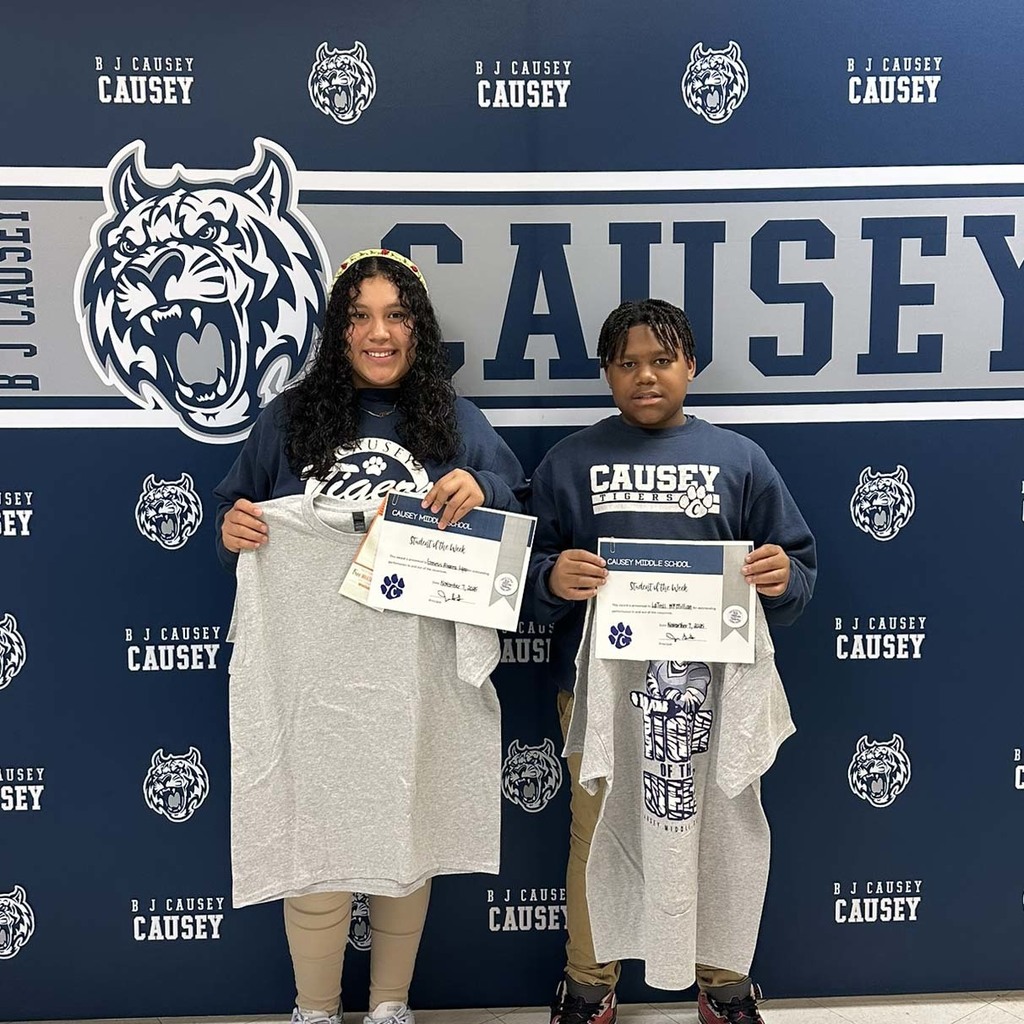 2 students holding up t-shirts and certificates