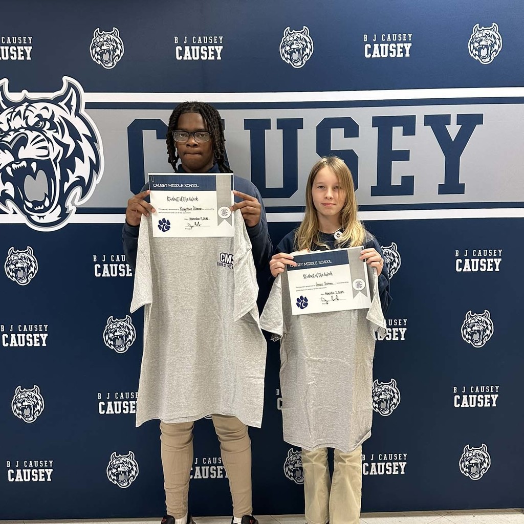 2 students holding up t-shirts and certificates
