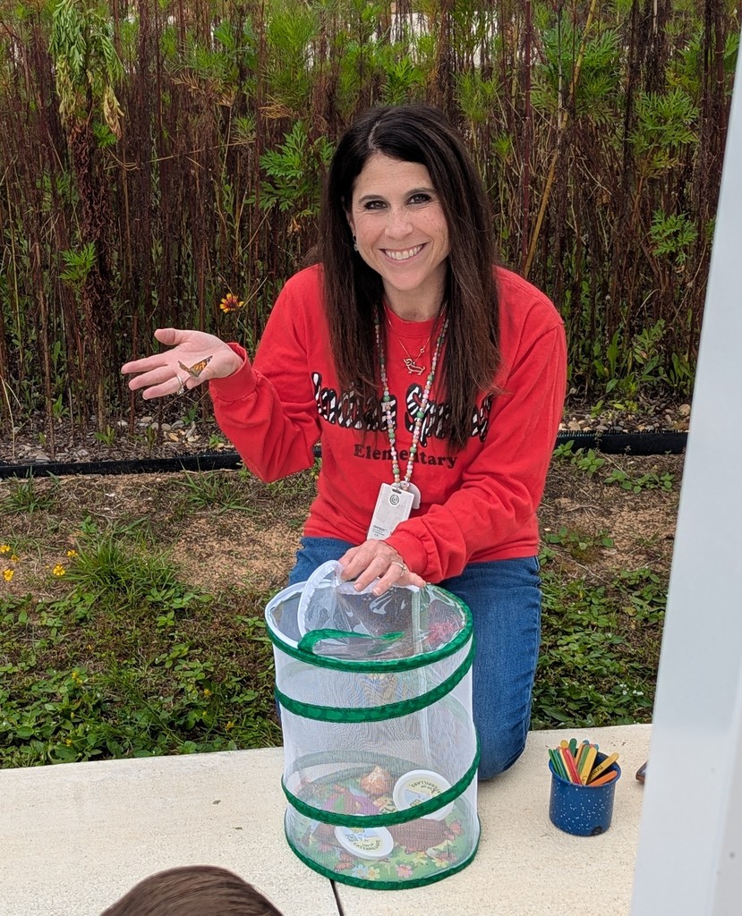 3rd grade teacher Ms. Green holding a butterfly and smiling