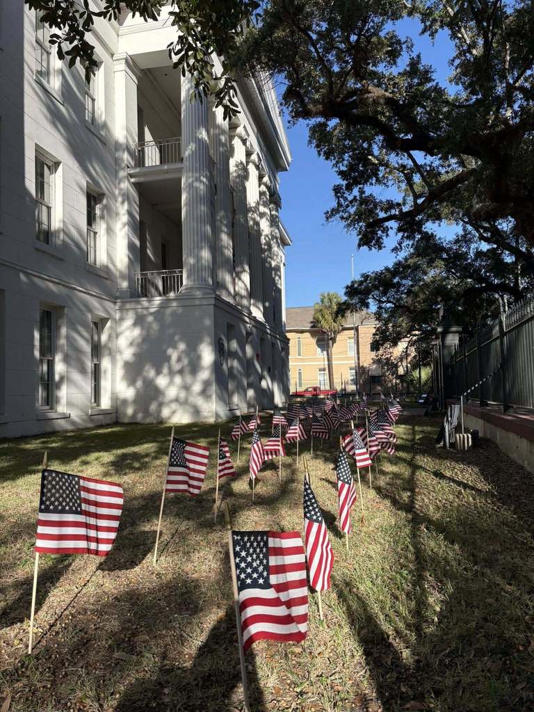 Small American flags stand in the grass in front of Barton Academy