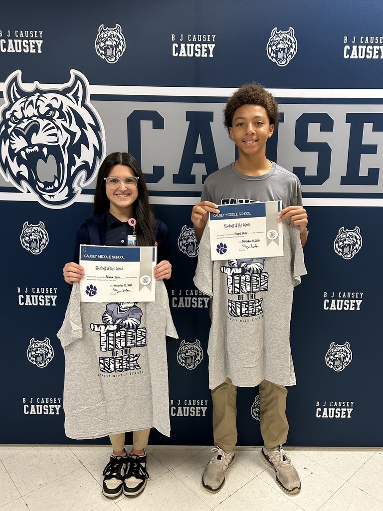 2 students holding up t-shirts and certificates