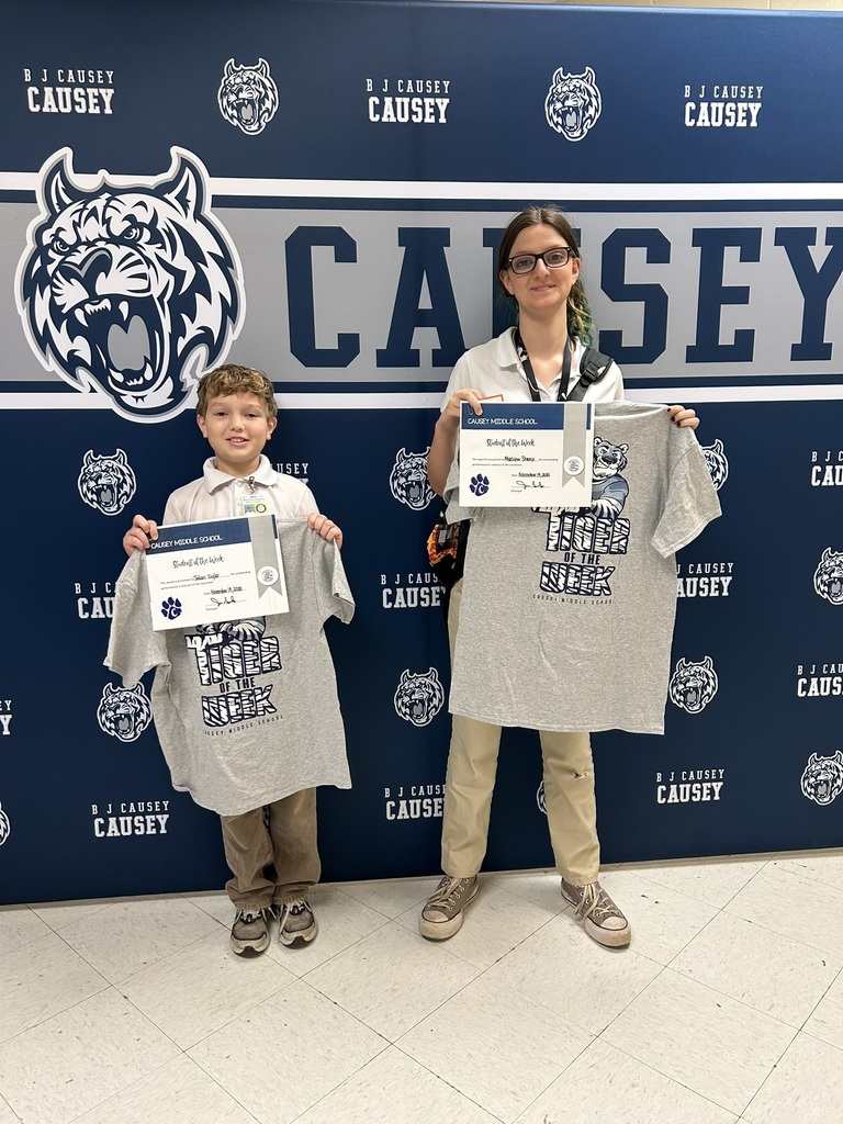 2 students holding up t-shirts and certificates
