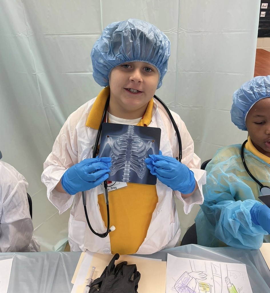 A student in hospital scrubs holds an X-ray of a ribcage