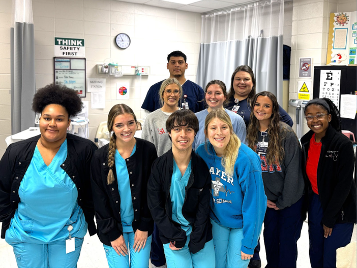 High school students pose with college nursing students in scrubs