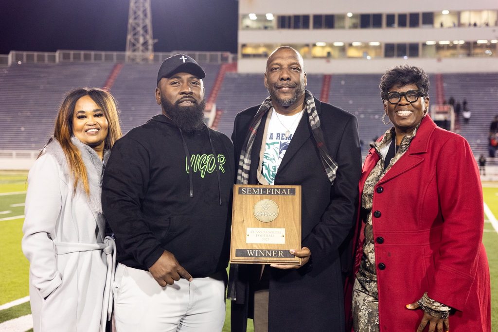 The Superintendent and deputy superintendent present  a Semifinal Winner plaque to Vigor's football coach and principal