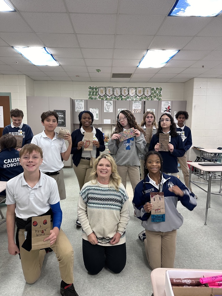 Group of students and teacher showing off their paper bags