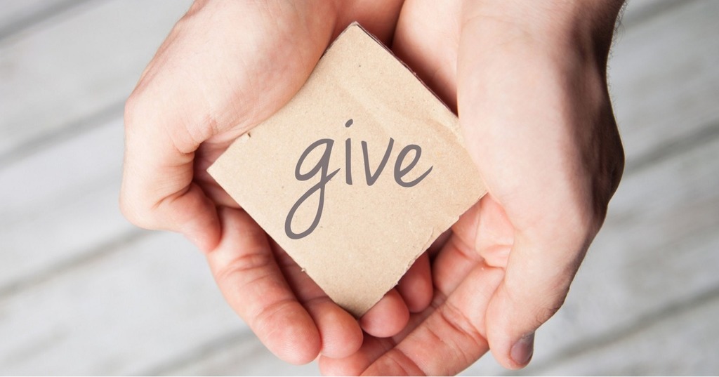 Hands holding sign that says Give.