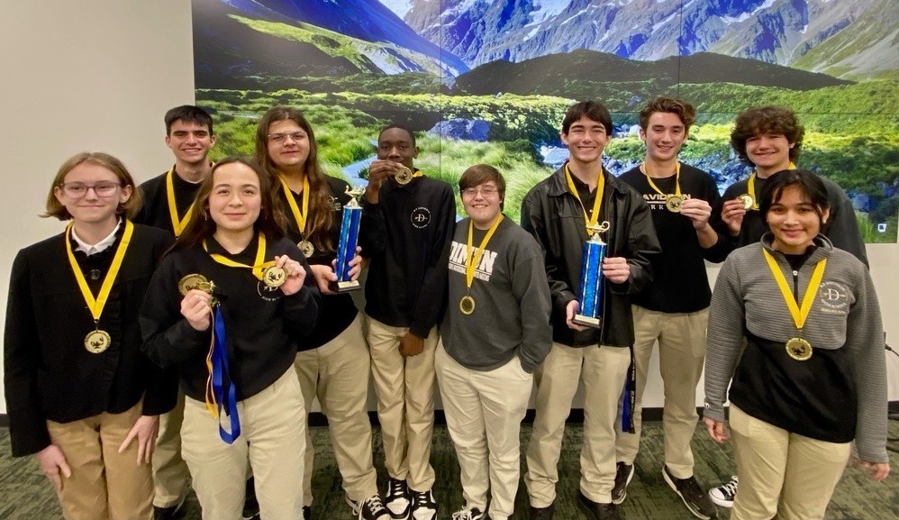 A group of high school students wearing medals and holding trophies
