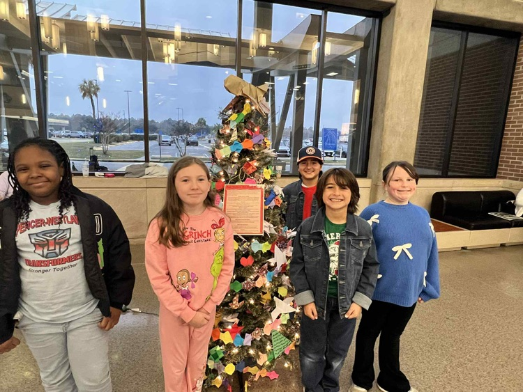 students posing in front of christmas tree of origami ornaments