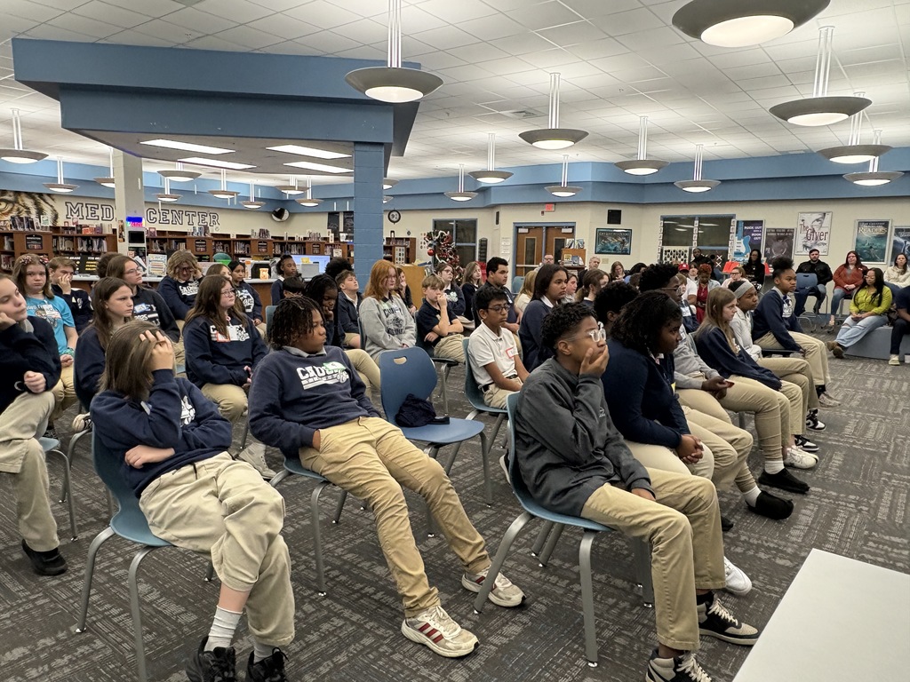 Group of students sitting in chairs in a library.