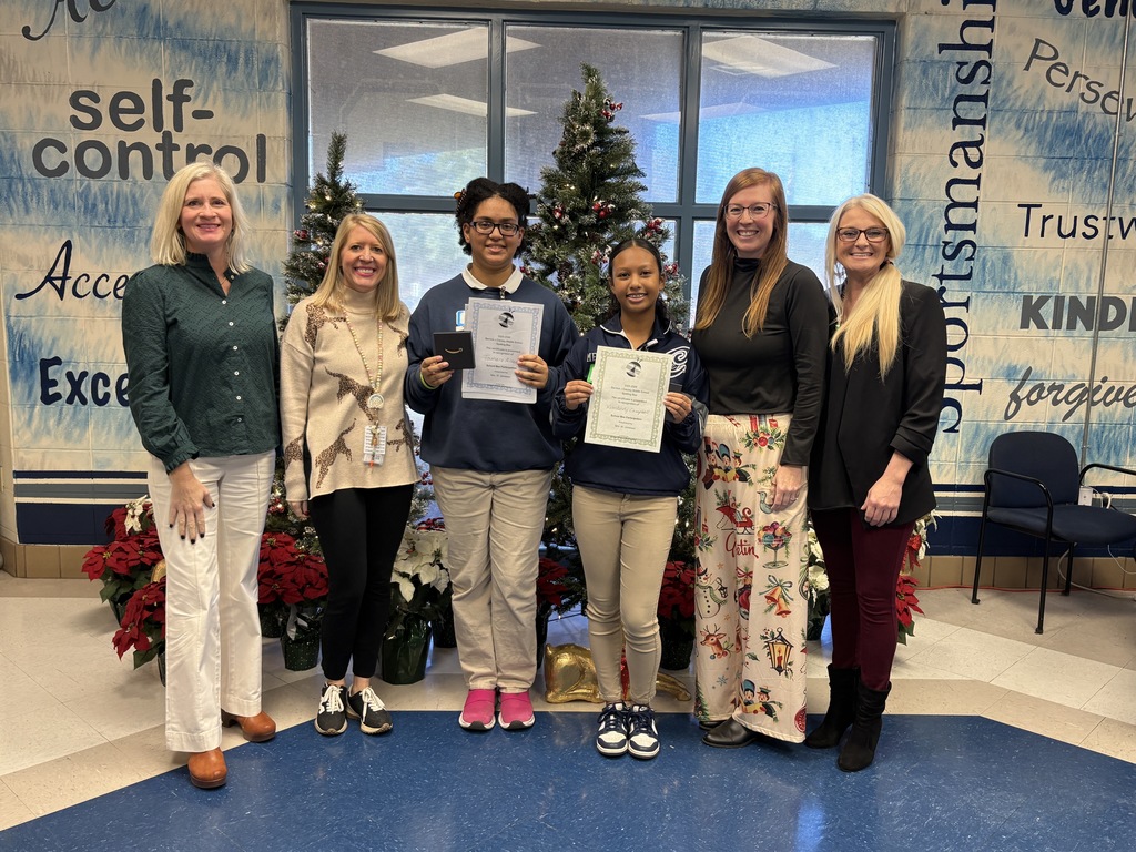 Group of women and girls standing in front of a Christmas tree.