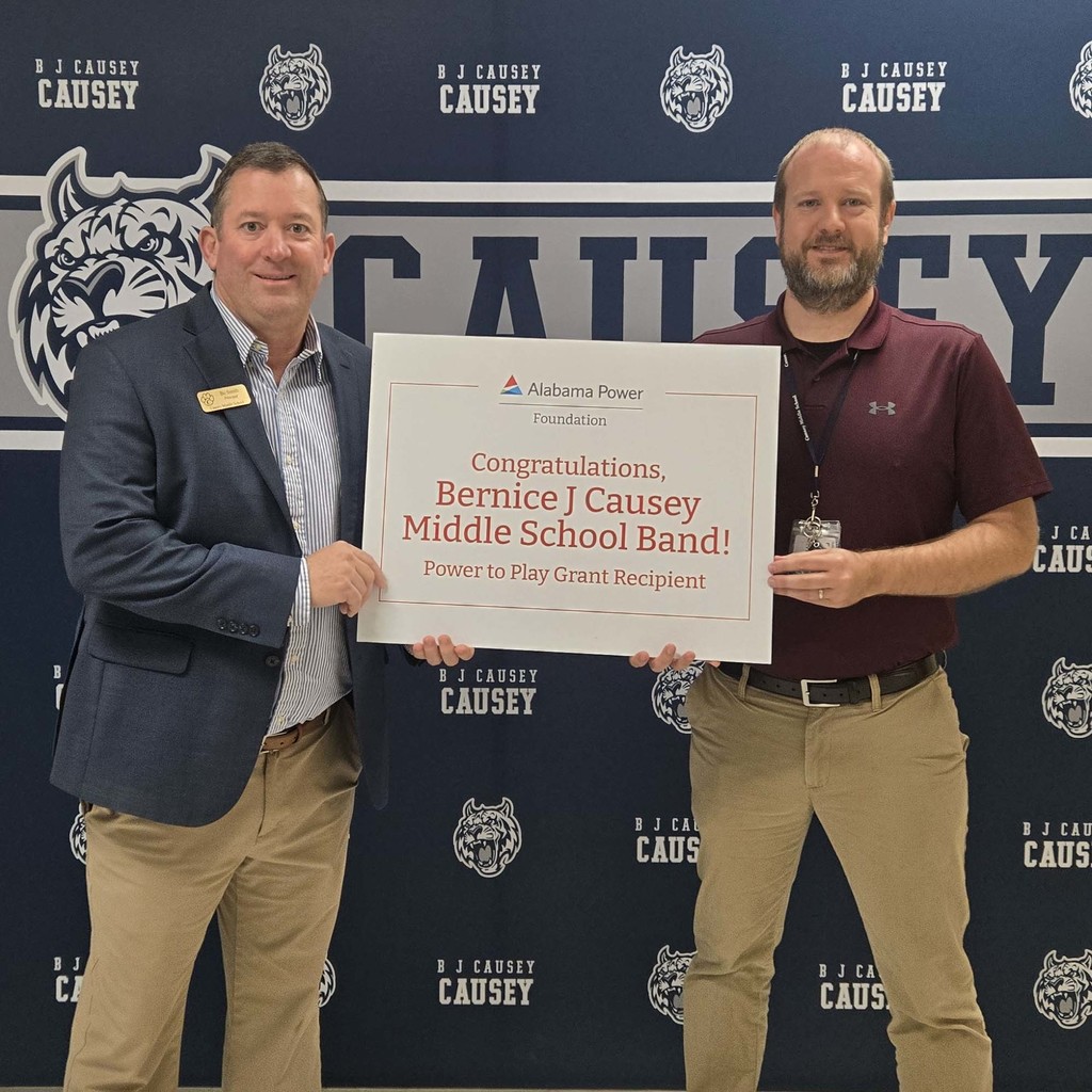 Mr. Smith and Mr. Threadgill standing in front of a backdrop holding up a sign that says congratulations to the band!