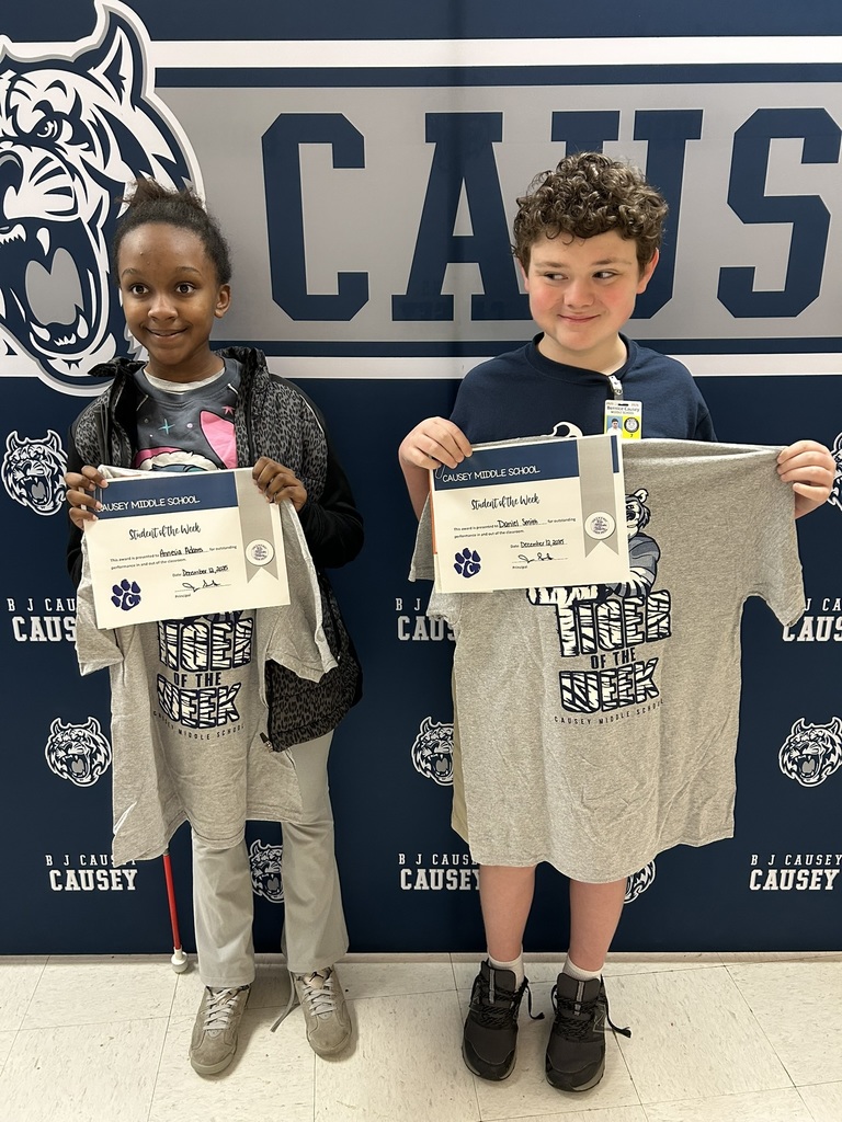 2 students holding up t-shirts and certificates