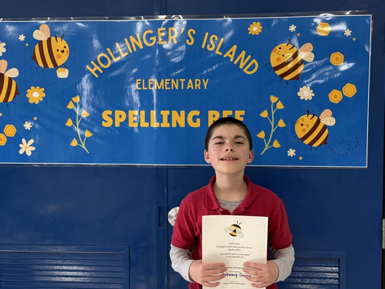 Johnny winning first place, holding his certificate in front of the Hollinger’s Island Spelling Bee banner