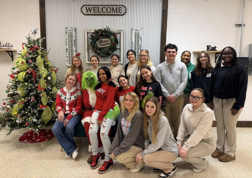 High school students pose with someone in a Grinch costume