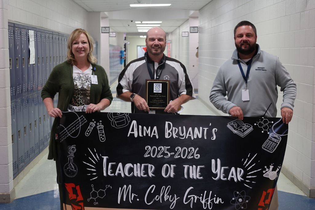 Three educators stand with a banner that reads: Alma Bryant's 2025-26 Teacher of the Year: Mr. Colby Griffin
