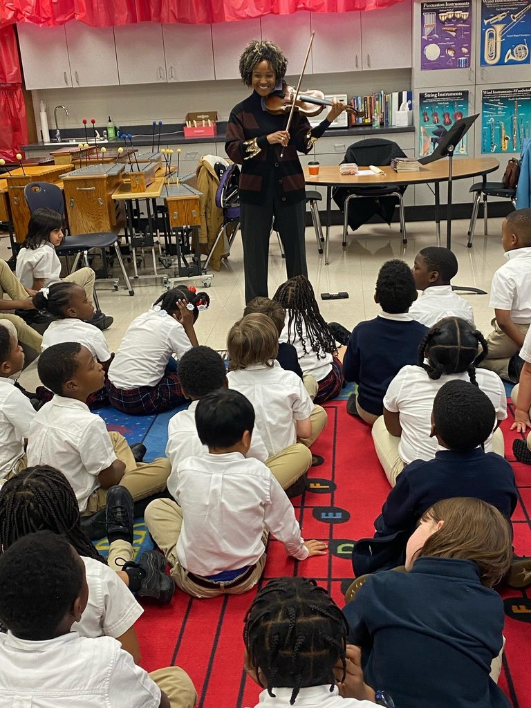 A woman playing violin in front of a classroom of students