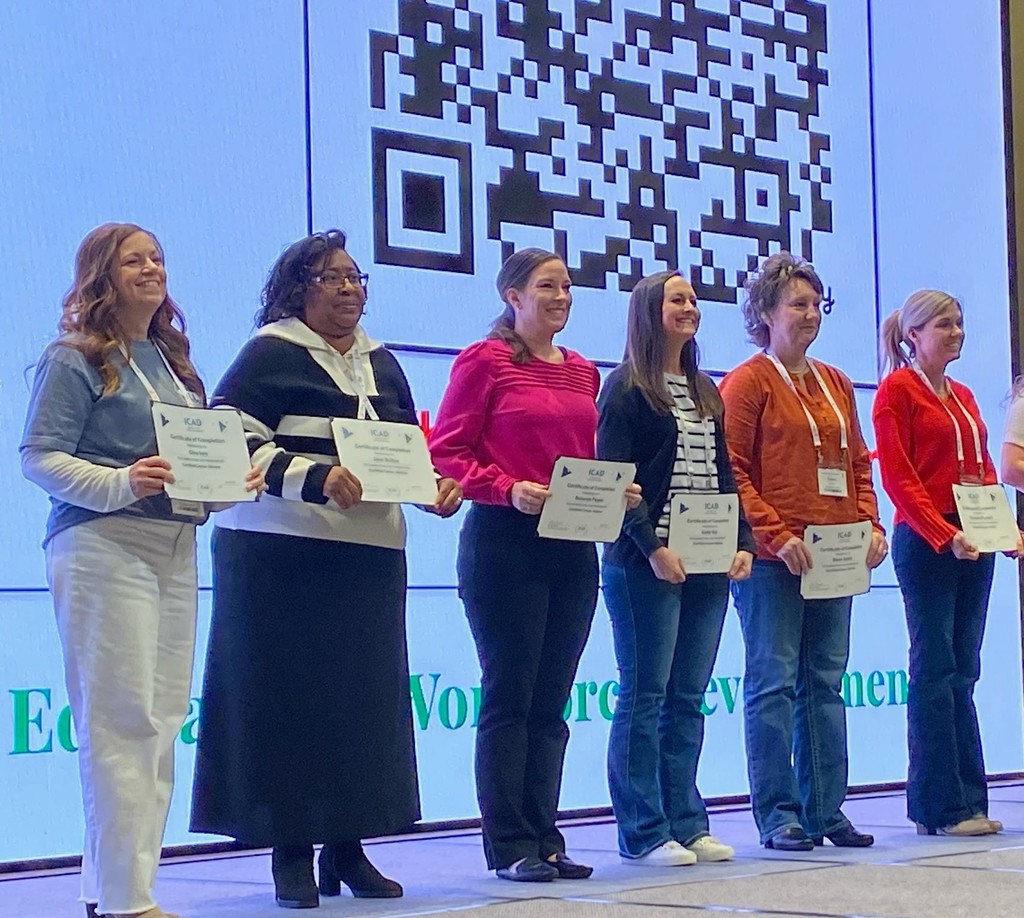A row of women holding certificates on a stage