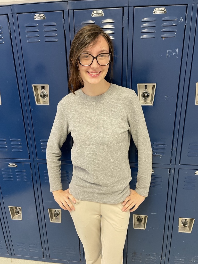 A high school girl standing in front of lockers