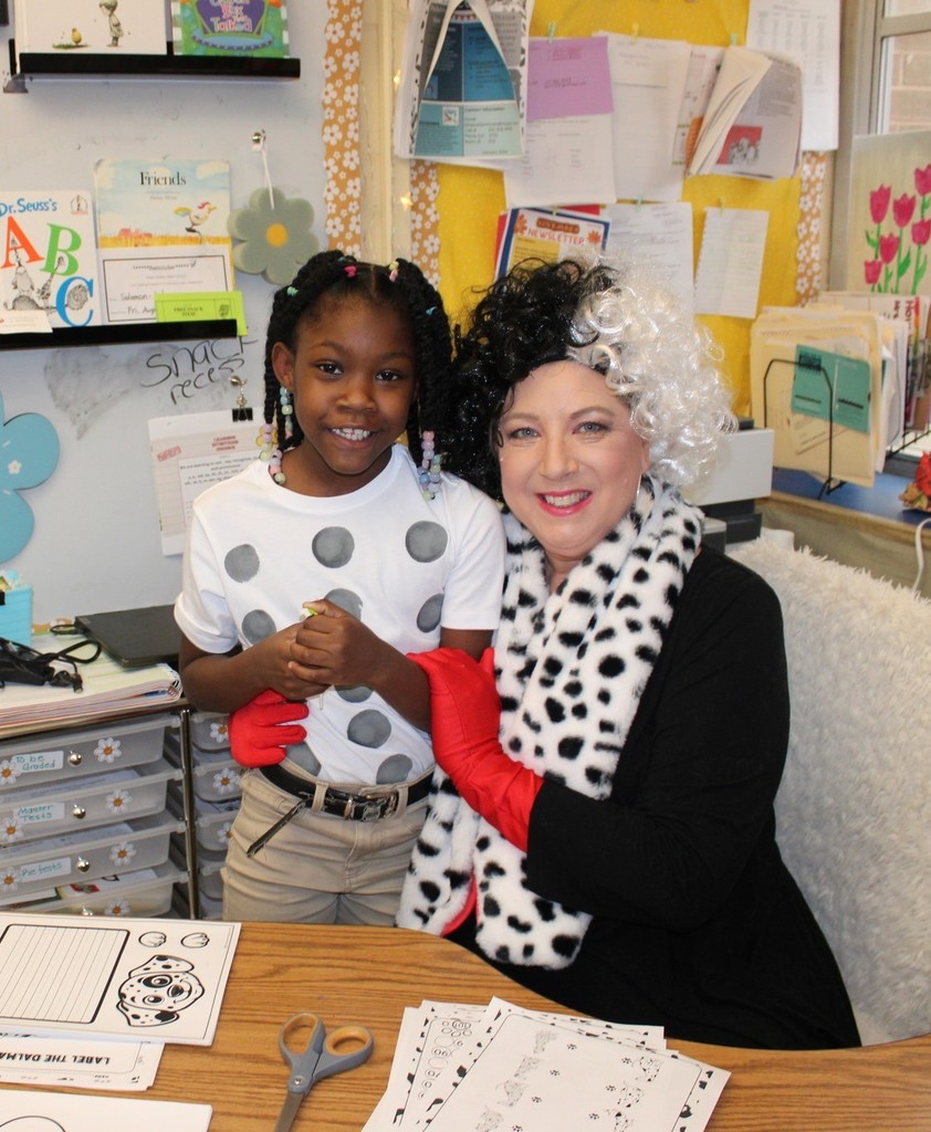 A teacher dressed like Cruella De Vil hugs a student dressed like a Dalmatian