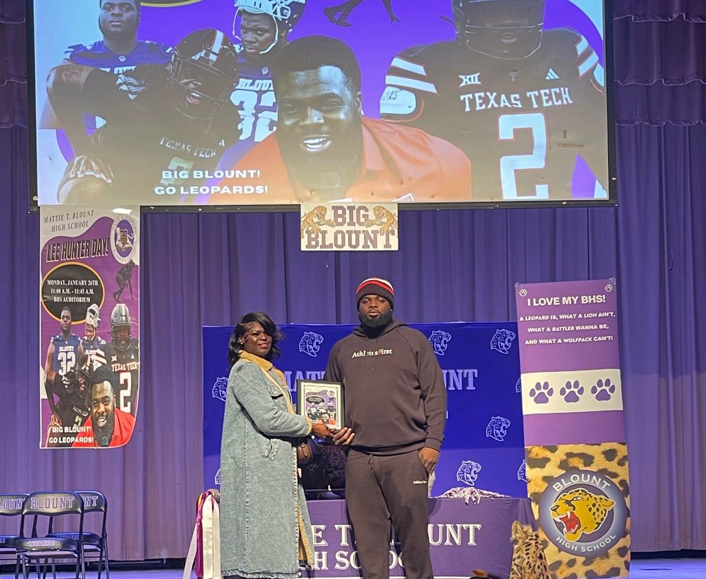 A woman handing a plaque to a man on a stage