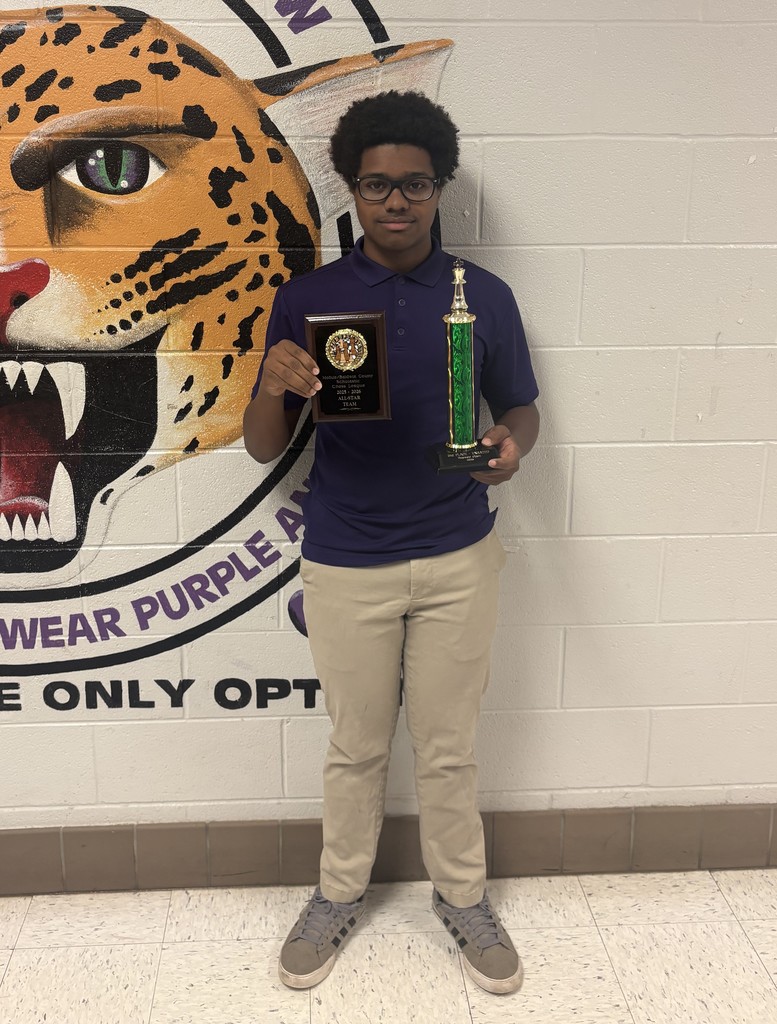 A high school boy holding a plaque and a trophy