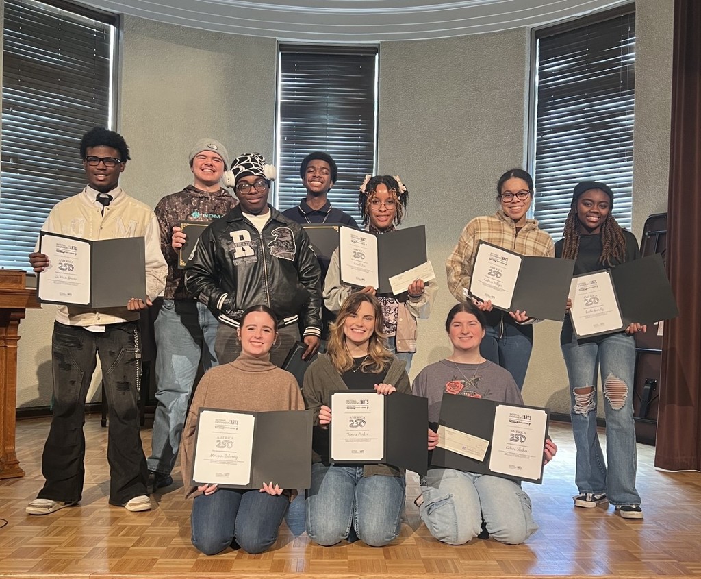 A group of high school students holding certificates on a stage 