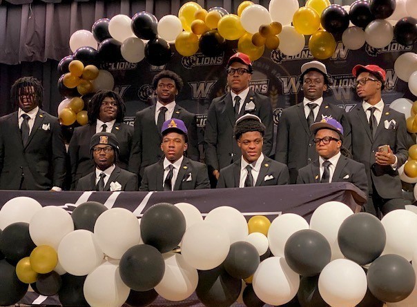 Ten high school boys on a stage, wearing black suits