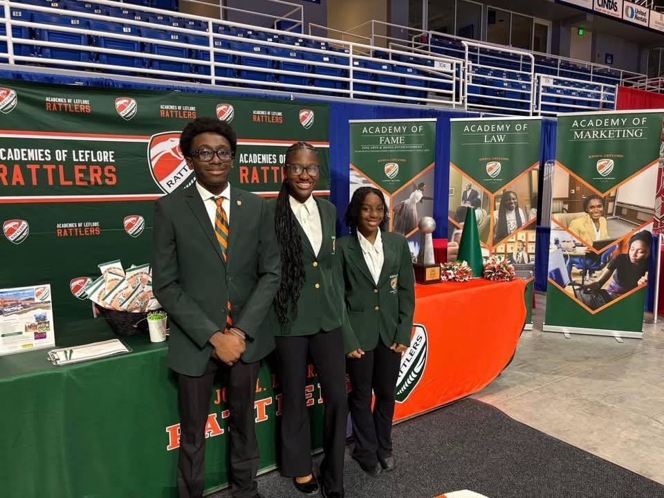 Three Leflore high school students standing in front of banners at the signature academy showcase.