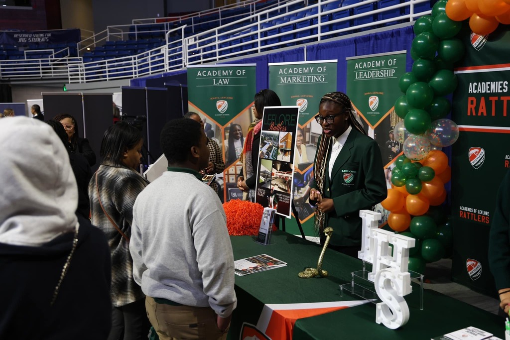 Leflore high school student ambassador talking to a student and a parent at the signature academy showcase.