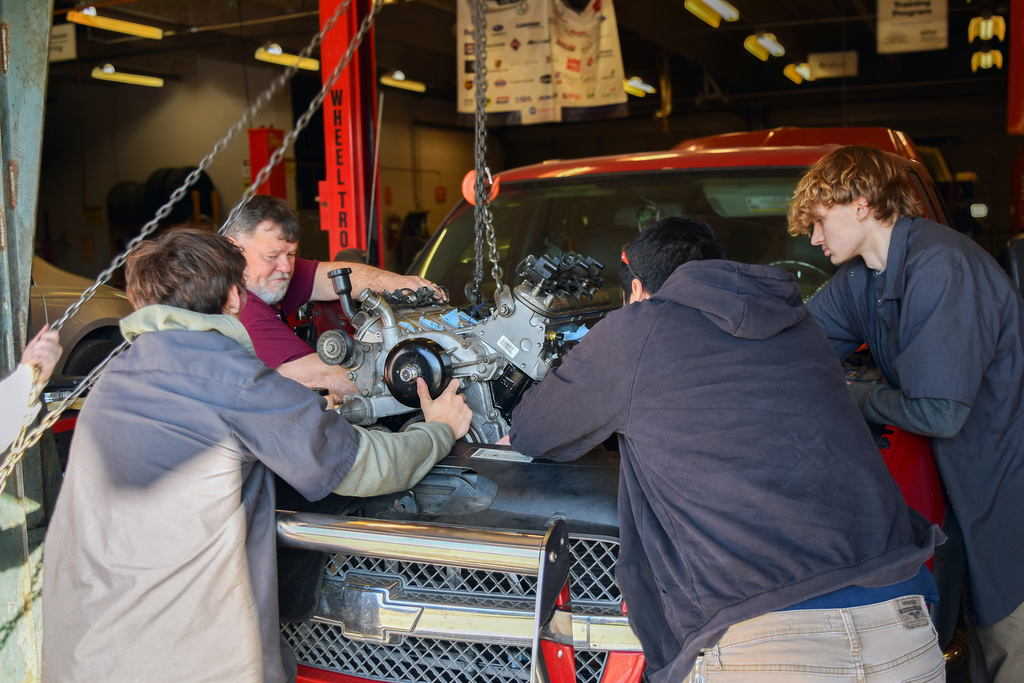 automotive students learning how to install a motor