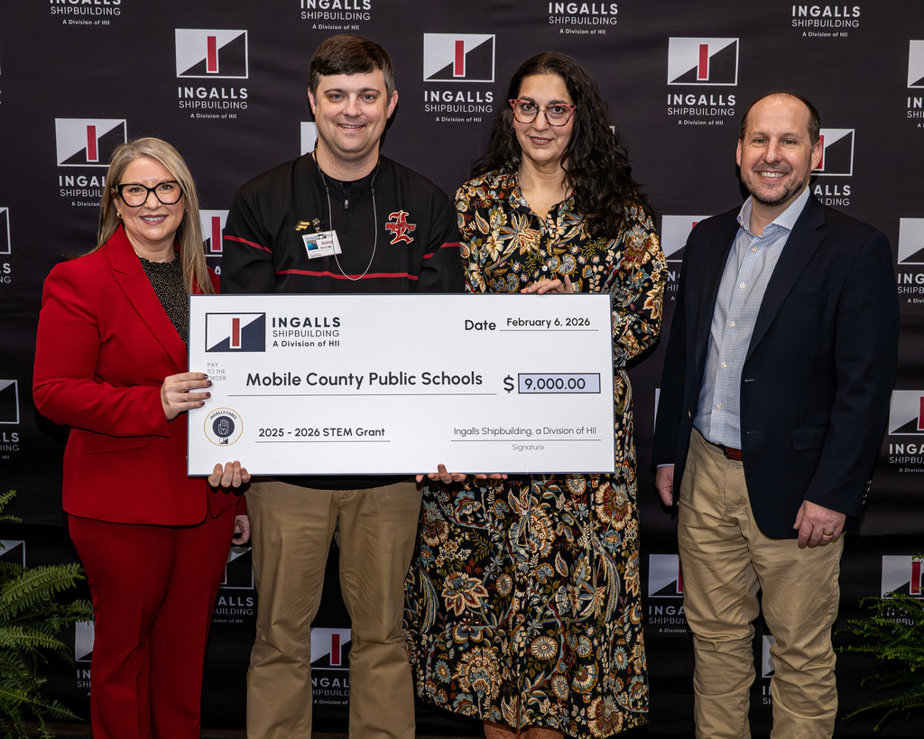 Two teachers and two other adults with an oversized check