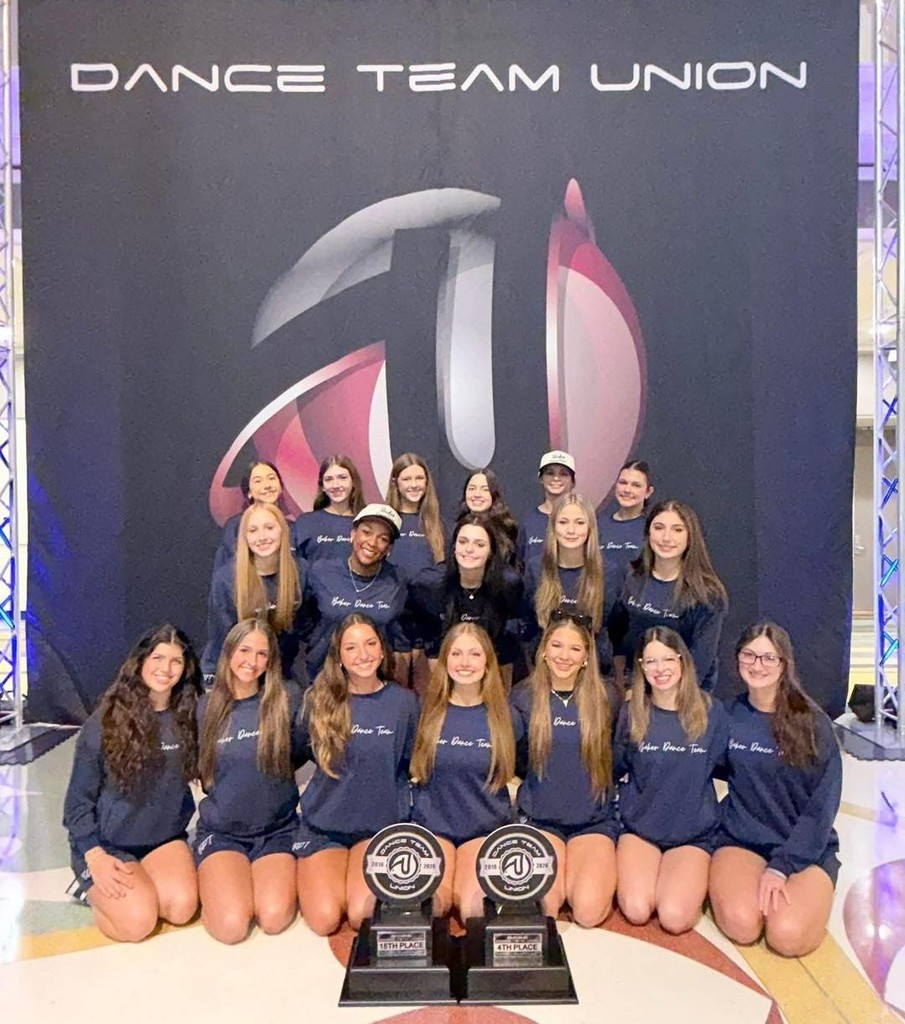 A group of girls with two trophies, posing in front of a banner that reads "Dance Team Union"