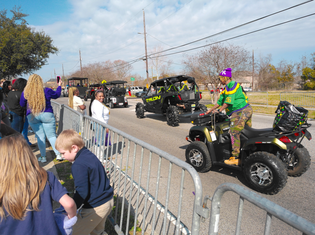 Parade floats moving down the street and teachers, staff, and students watch