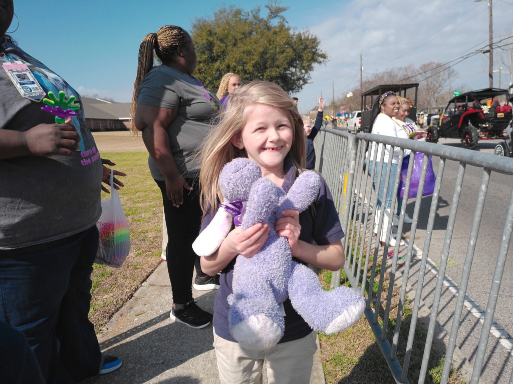 A student holding a stuffed animal they caught at the parade 