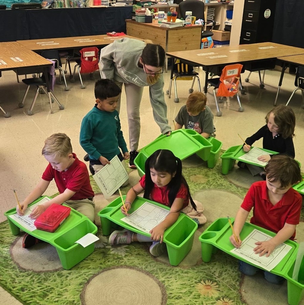 A high school student sets out study boards for elementary students, who are seated on the floor