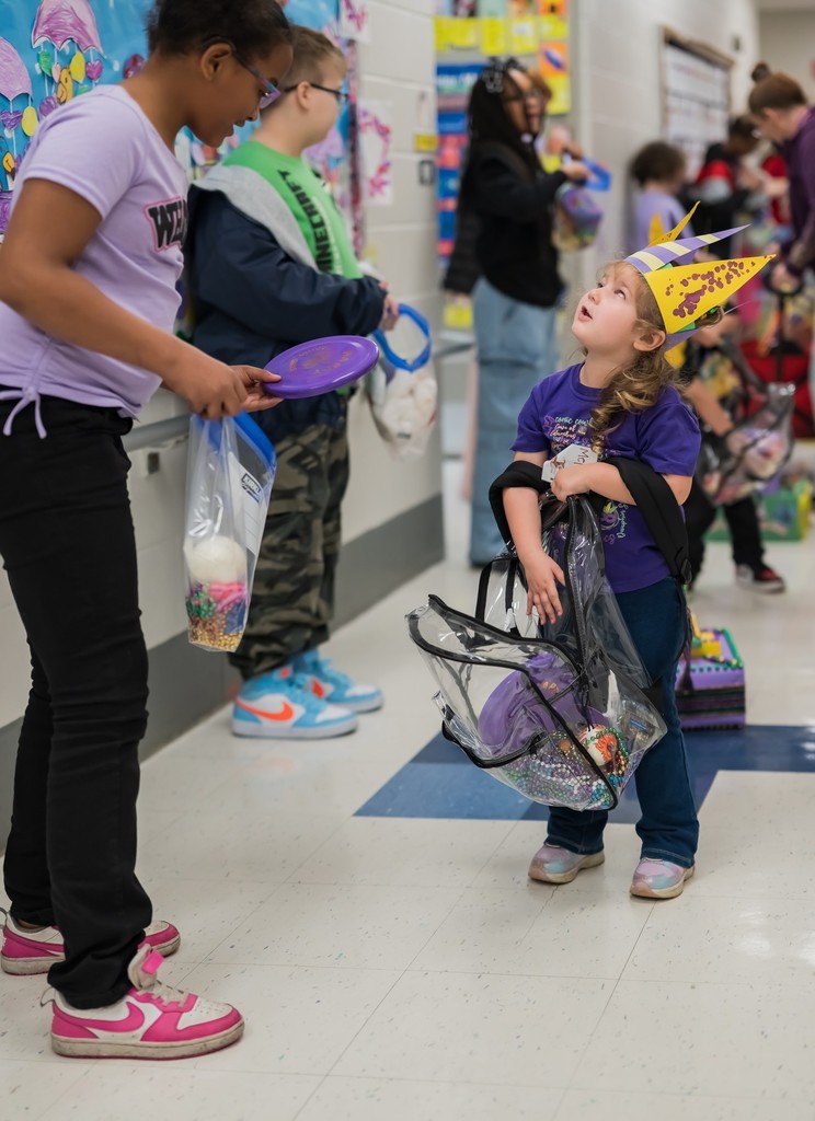 A girl reaches in her backpack as a bigger girl looks on 