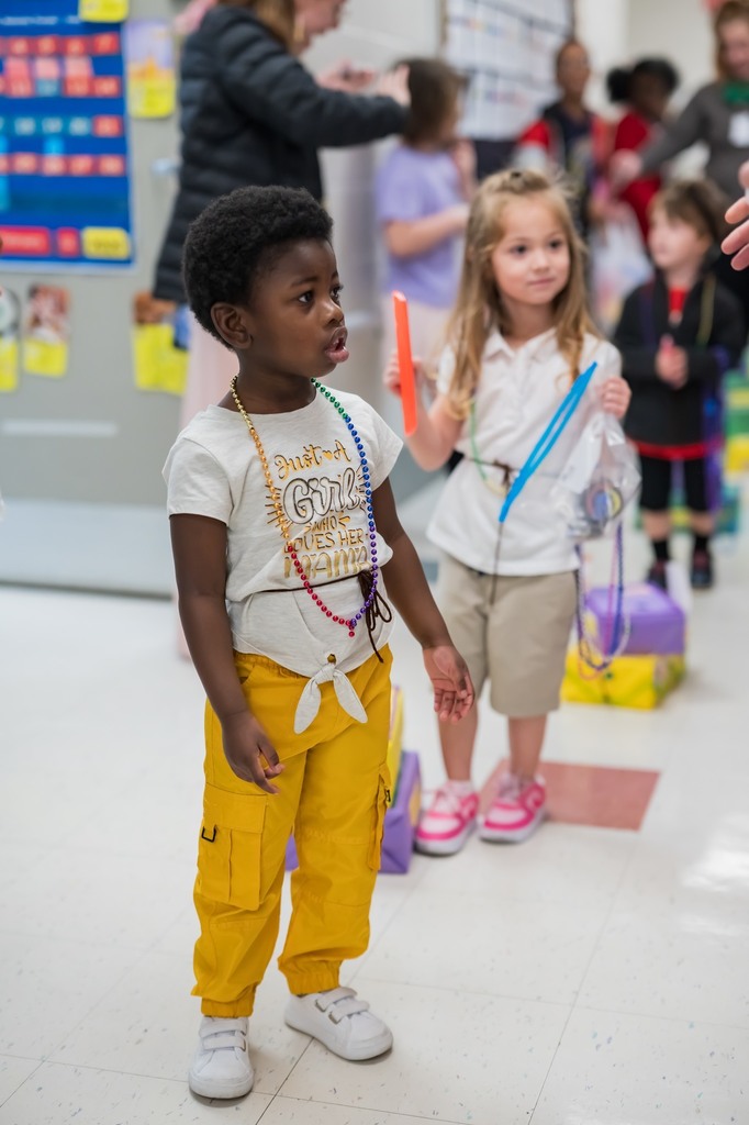 Two girls walking in a hallway with Mardi Gras beads on