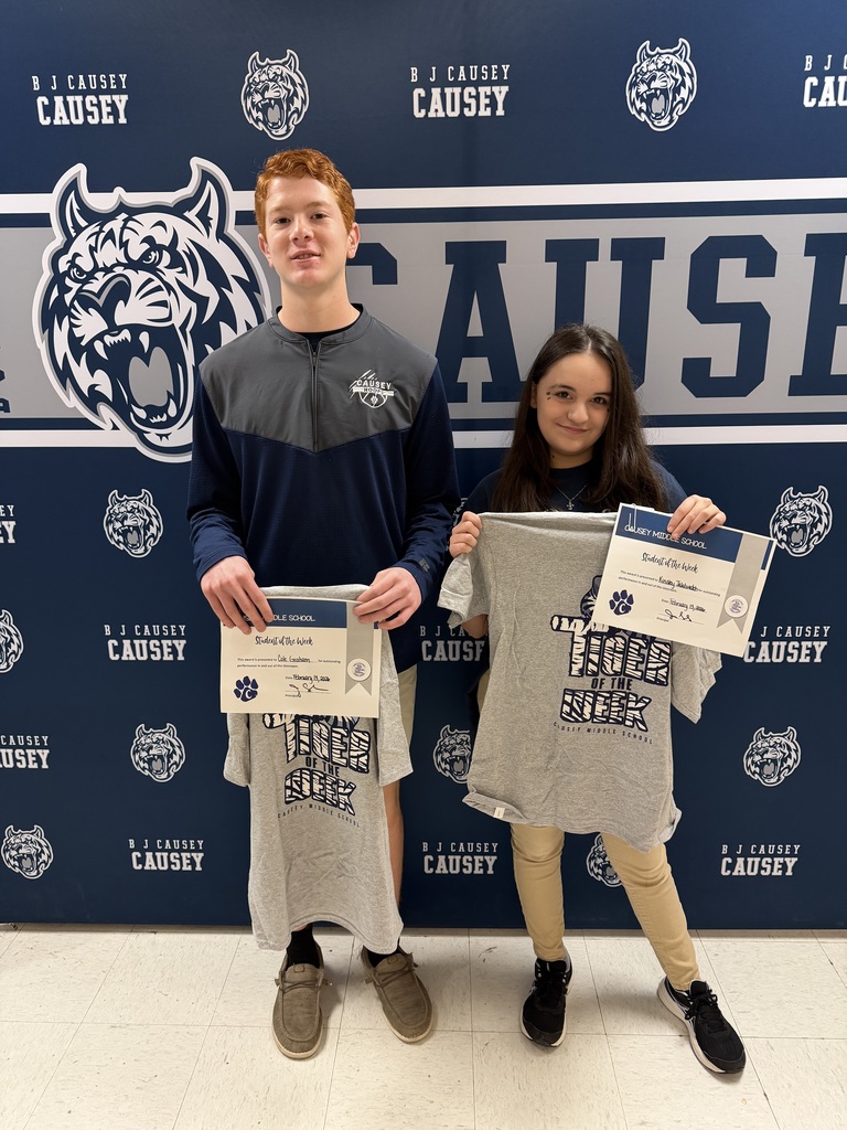 2 students holding up t-shirts and certificates