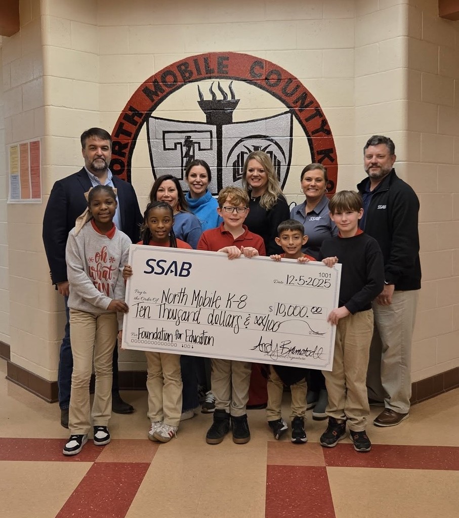 A group of students and a few adults, with an oversized check for $10,000 made out to North Mobile K-8
