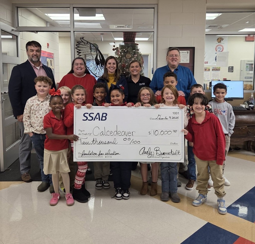 A group of students and a few adults, with an oversized check for $10,000 made out to Calcedeaver